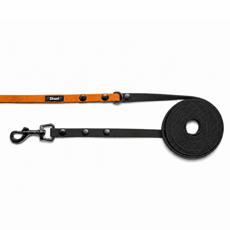 A dog leash with a black padded strap, silver metal hardware, and an orange handle, shown on a clean white background.
