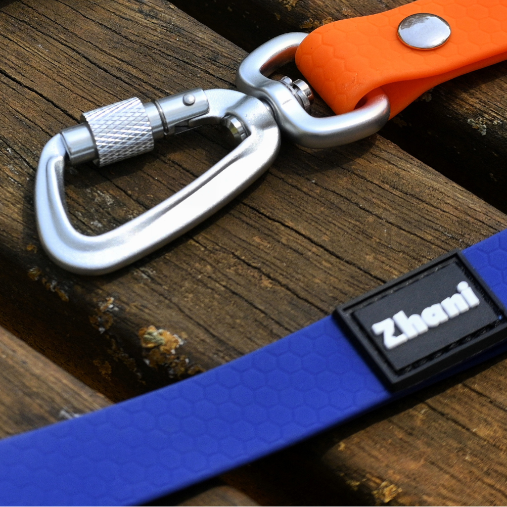 Blue strap with carabiner and orange clip on a wooden surface, featuring the brand 'Zhen'.